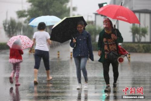 资料图：民众在雨中出行。