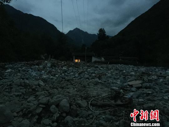 8月10日晚，夜幕降临，姚世梅夫妇从安置帐篷里回家拿衣物。他们家的房子在泥石流冲刷过的废墟旁，孤零零的亮着一盏灯，很快就灭了，他们说，再也不敢搬回家住了。　南如卓玛　摄